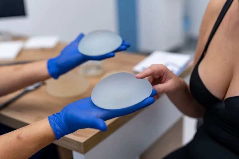 Patient choosing silicone breast implants with doctor. Woman with doctor examines silicone breast implants during consultation in a modern clinic.